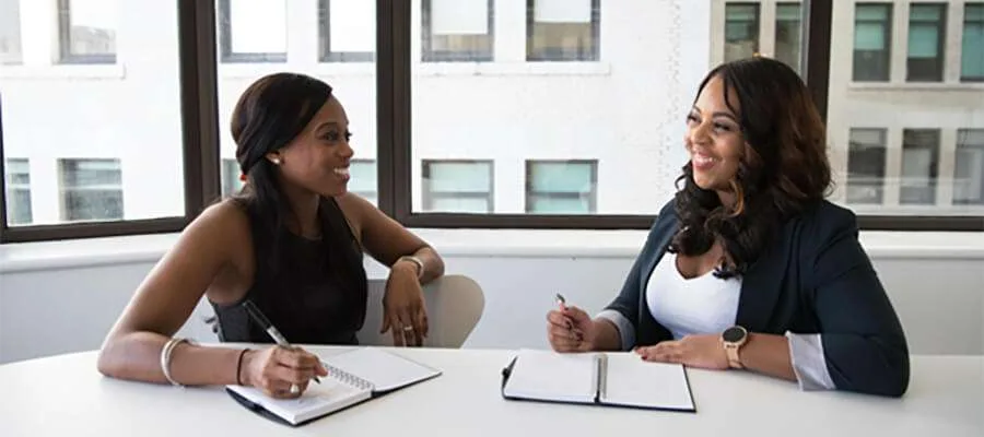 two black women discussing and taking notes