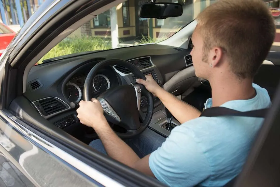 Young boy driving a car while carefully looking at the road