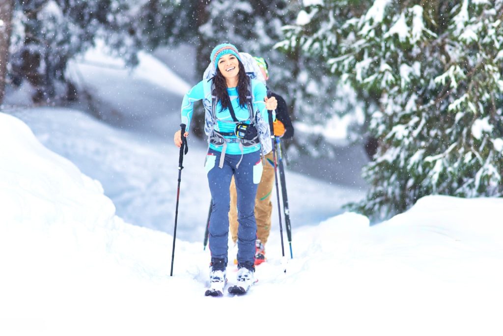 a happy girl ski touring in the woods during snowfall