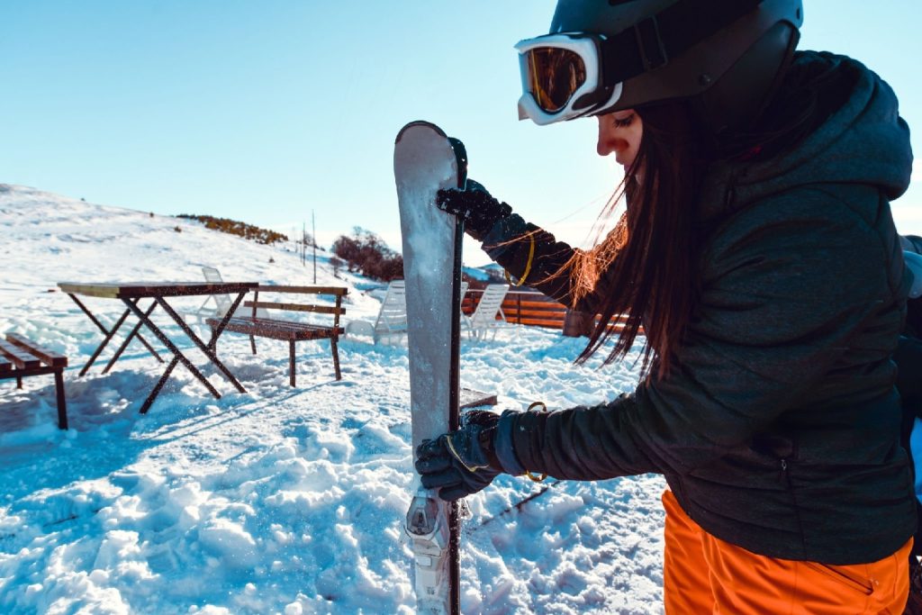 woman skier carefully looking at her ski