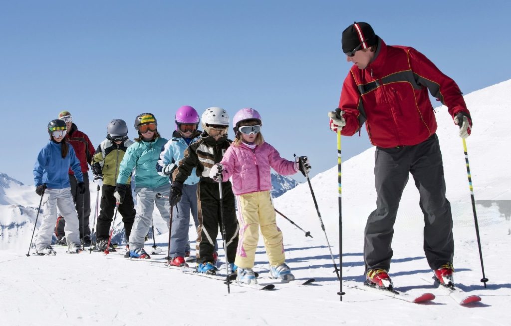 ski expert teaching skiing skill to kids