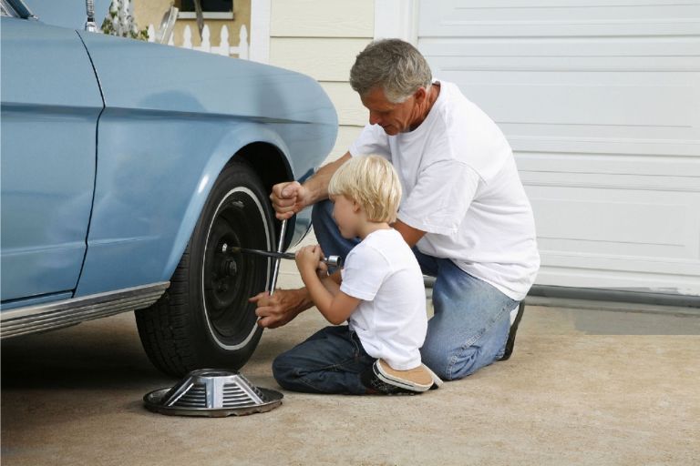 Father and son working on the vintage car tire