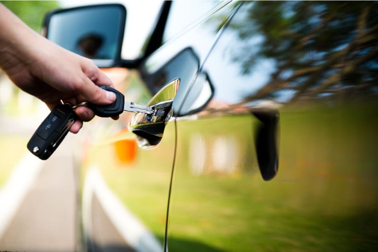 man inserting key in car door lock