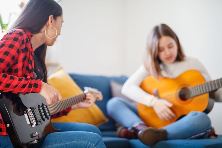two young ladies playing guitars